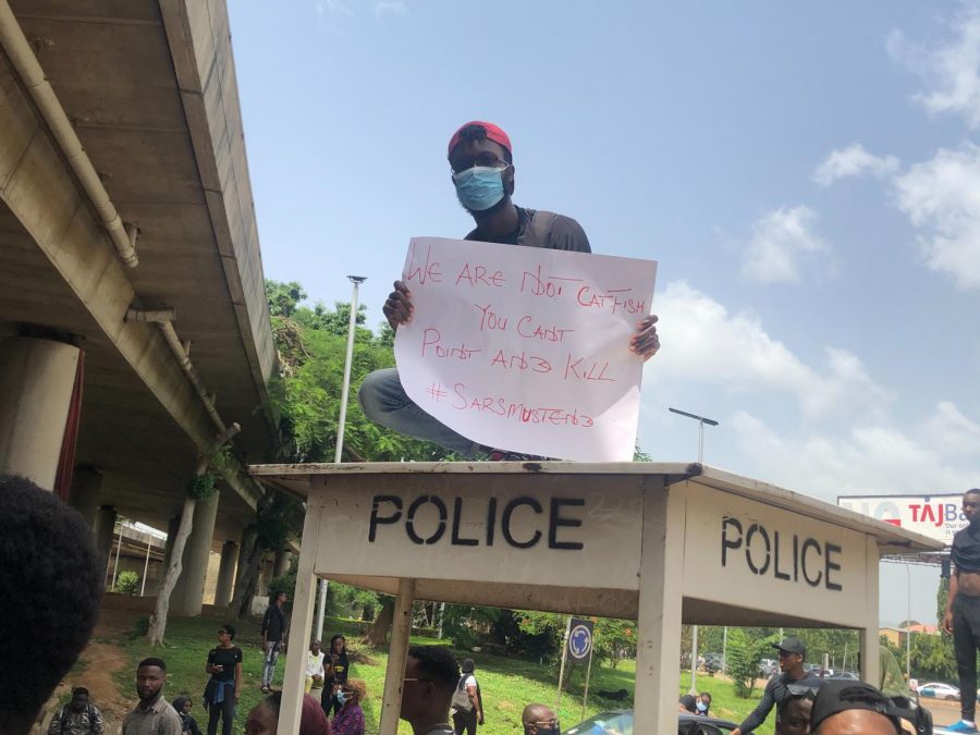 EndSARS Protester in Abuja, Nigeria; a man holds a sign with the text We Are Not Catfish You Cant Point And Kill #SARSMustEnd while protesting the SARS organization