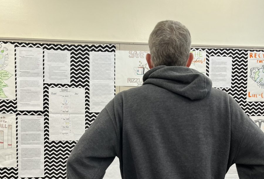 Mr. Rose admires the sophomore projects pinned to his classroom walls.