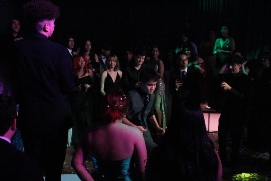 Justin Mayoralgo dances and does flips surrounded by a ring of students including Brittany Ruvalcaba, Joseph Mayoralgo, Ulysses Carillo, and others. 
