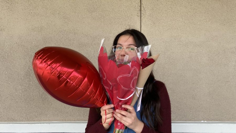 Sofia Hernandez holding a heart-shaped balloon and many Valentines flowers. 
