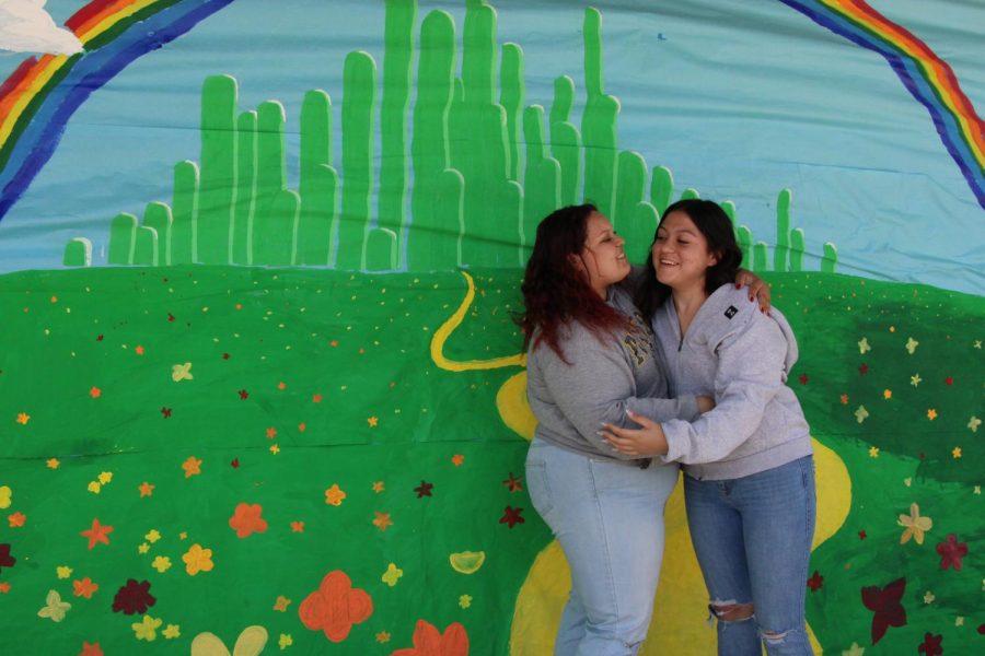 Eliza Vasquez and Stephanie Balanzar embrace eachother beneath the Emerald City rainbow.