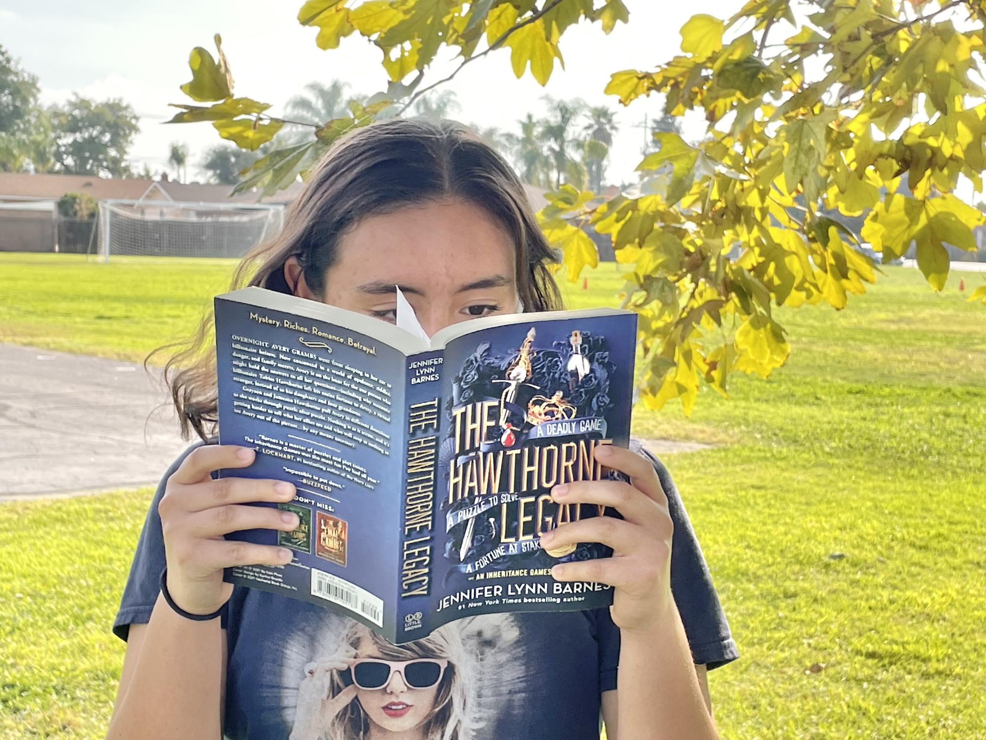 Bella-Tavera-Gonzalez reading her newest novel, The Hawthorne Legacy by Jennifer Lynn Barnes. 
