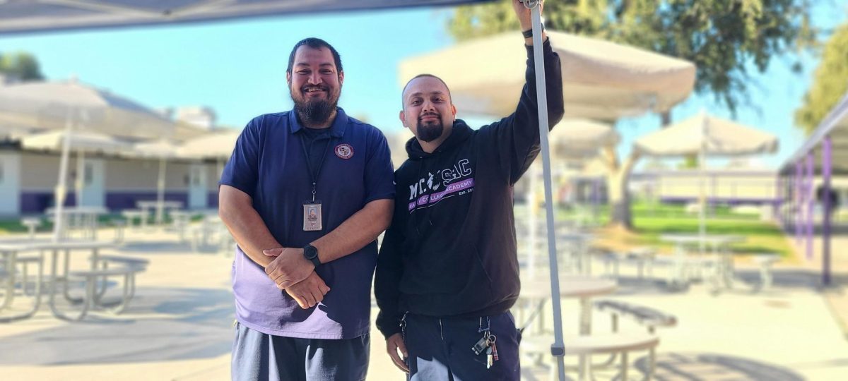 Security Guard Alex Palacios and custodian Joshua Del Real smiling wide after setting up the easy-up for the lunch line. 
