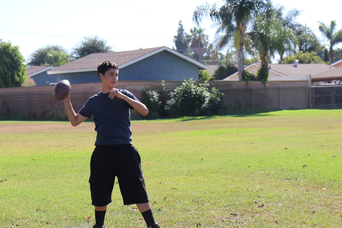 Winding up for the perfect throw, ninth grader Brandon Rosales practices throwing the ball during the football tryouts. He raises the ball high and aims for the goal, he practices it a few times until perfection.