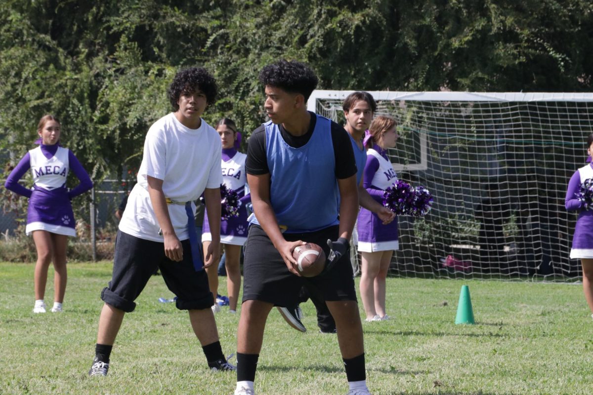 Albert Martinez (9), Ari Tejada (9), and Felix Acevedo (10) play football in MECA's first  House Competition for the 2024-25 school year with cheerleaders, Isabel Fulmer (9), Cindy Monjaraz (9), and Sadie Mcbean (12) cheering everyone on.