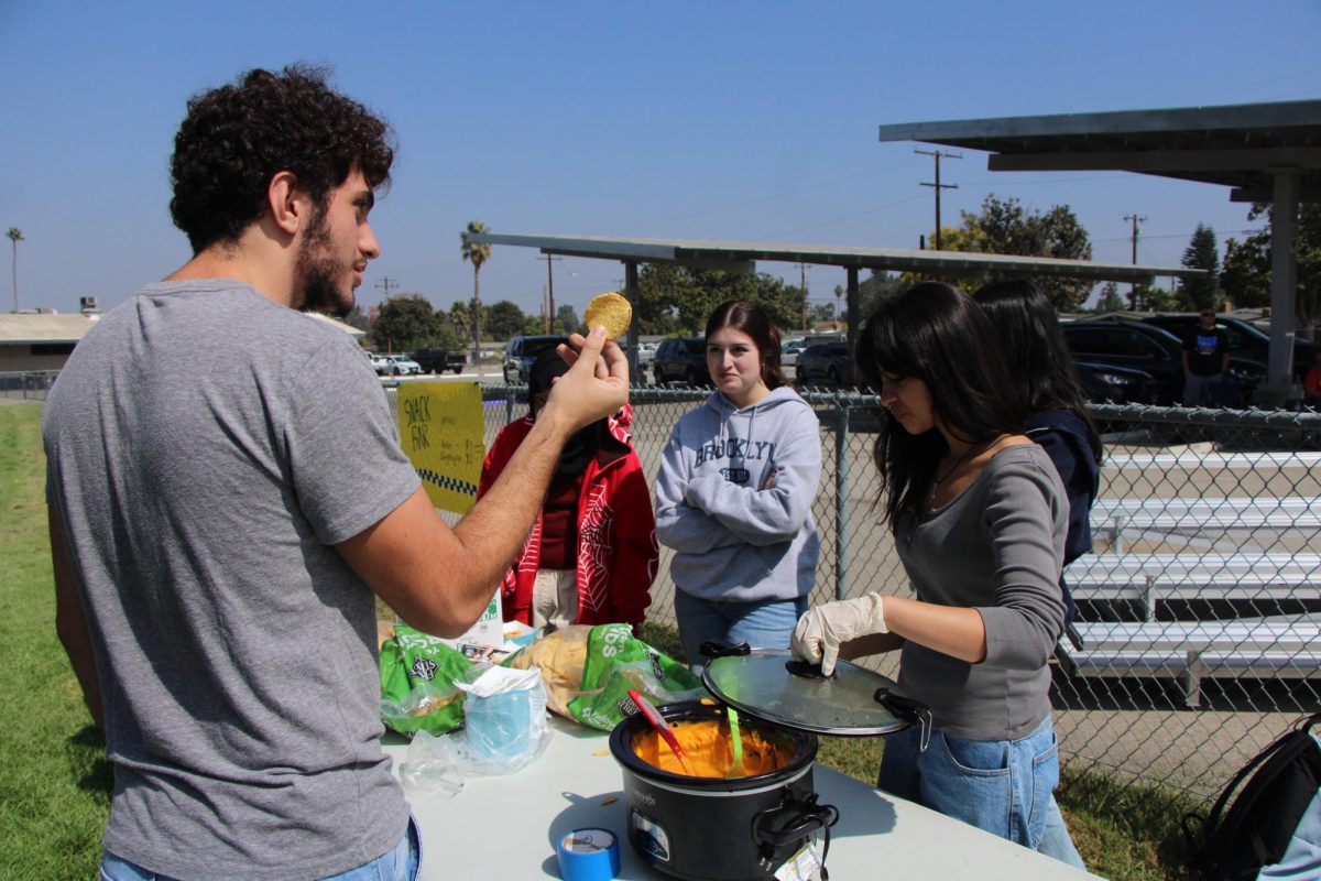 It's too pricey!!! Angelo Karsouny (12) playfully argues with Jocelyn Pena (9) and Audrey Spencer (12) about the price of the nachos! He picks up a chip and jokingly complains about the nachos.
