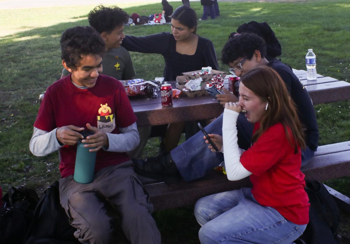 Charlotte and her friends, Miguel Orozco, Albert Martinez, Krista Pena and Marvin Lopez joke around on the table under the trees. Miguel and Charlotte wear red to participate in the Red Ribbon Spirit Week. Emmelynn Manuel says, “A lot of people are always around her, I see, like want to be her friends and stuff.”