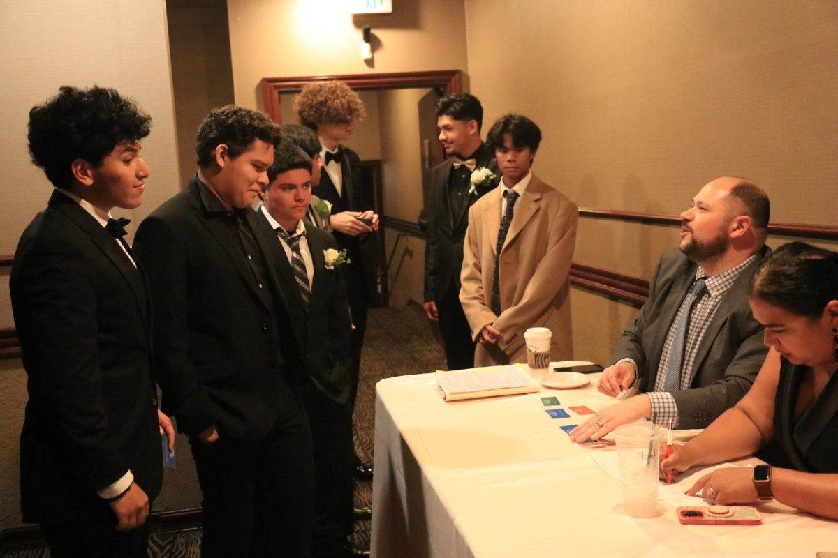 Dominick Gonzolas (12), Pedro Lopez (12), Jesus Vazquez (12), Blake Bastian (12), Damian Mejia (12), and Ronald Pajeronne (12) are waiting to be checked in for prom by Principal Ryan McDonnell and Assistant Principal Katarina Garcia.