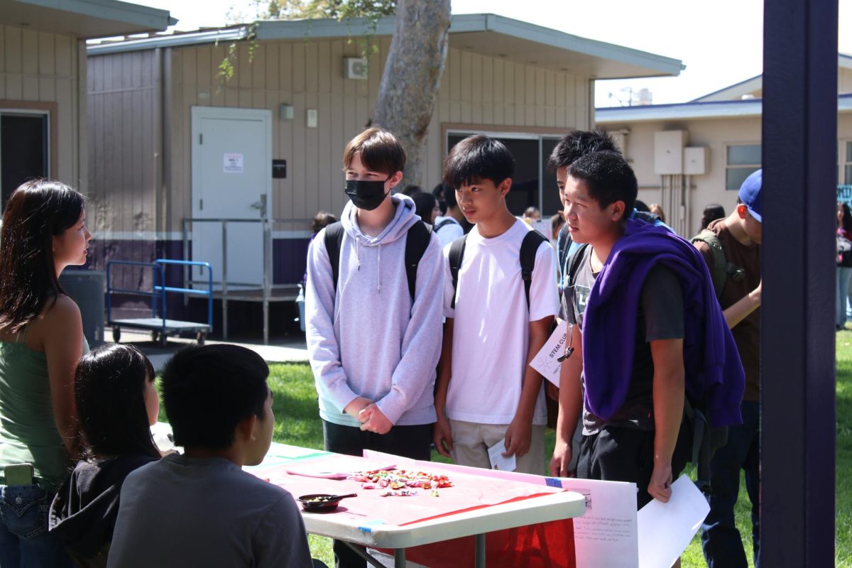 Ryan Huynh (9), William Liu (9), and Ethan Bymaster (9) looking at clubs during club rush.