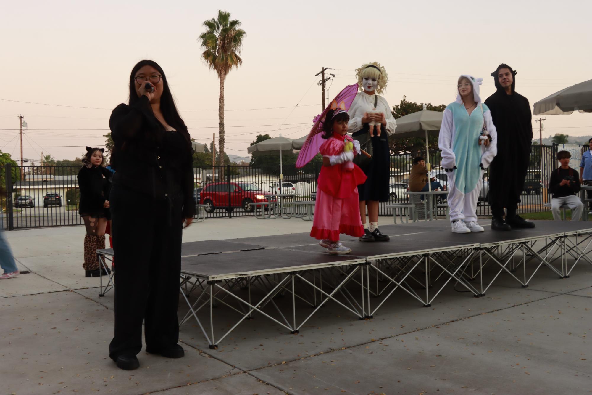 Katelynn Lee (12) announces the costume contest finalists Krista Pena (10), Sadie McBean, and Felix Acevedo (11).