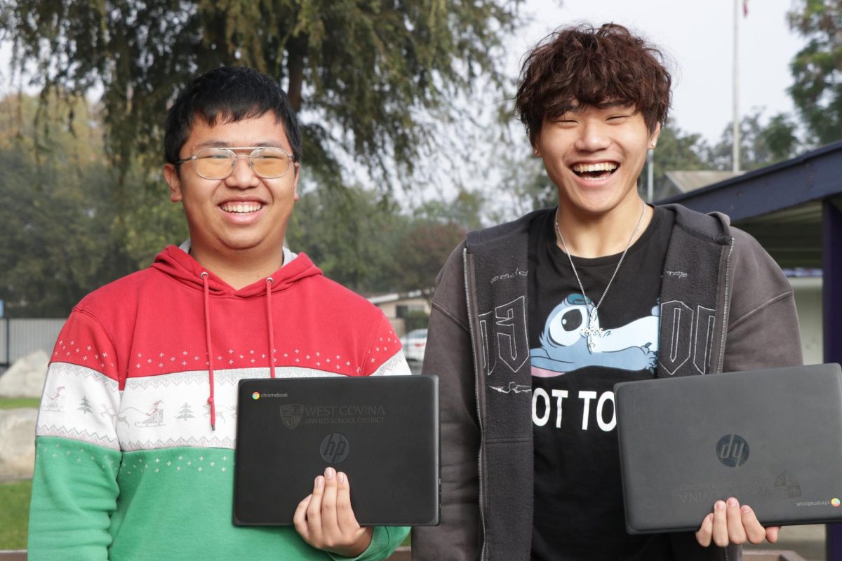 Charlie Zhu and En Hao Xie pose with their district-provided computers. "For me, it feels like a bit too much," said Zhu. "As long as the student is not going to harm the school property, there should not be restrictions."